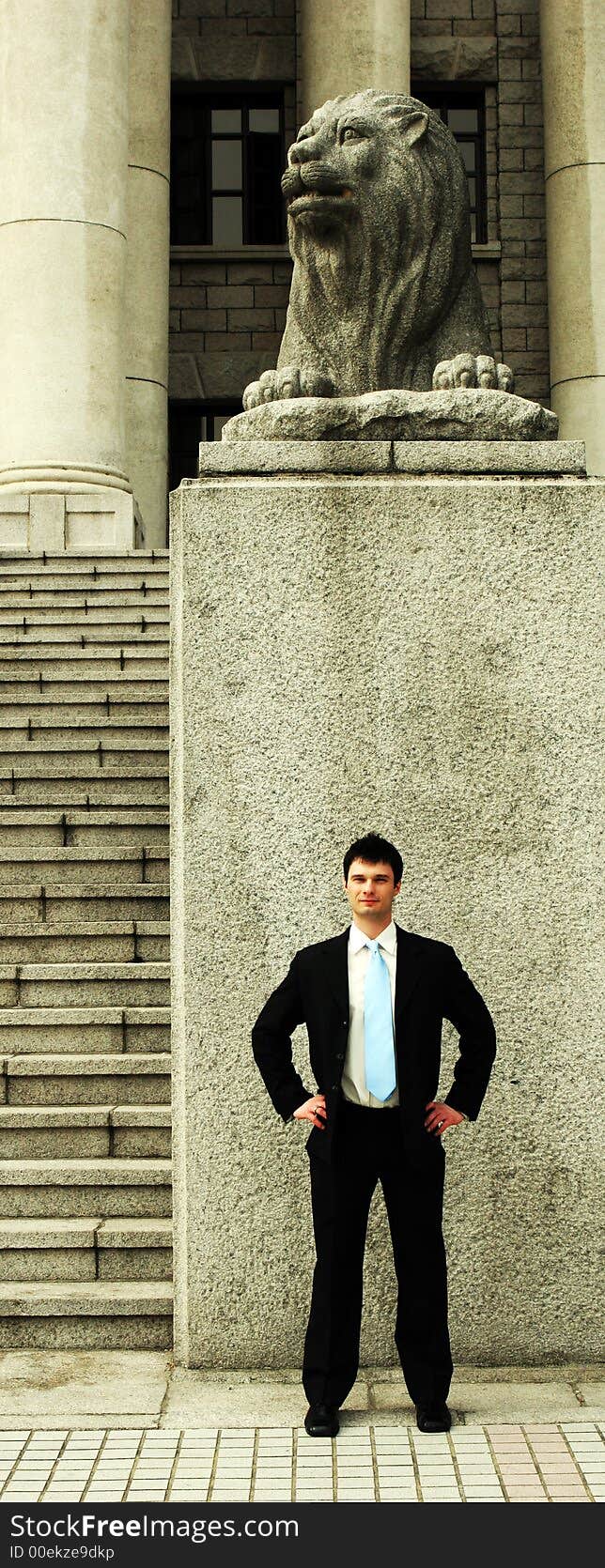 Businessman standing in front of a lion statue. Businessman standing in front of a lion statue