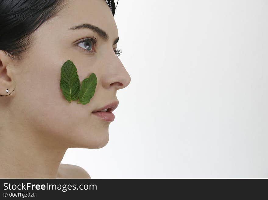 Beautiful woman with two leafs of green mint on hear cheek. Beautiful woman with two leafs of green mint on hear cheek.