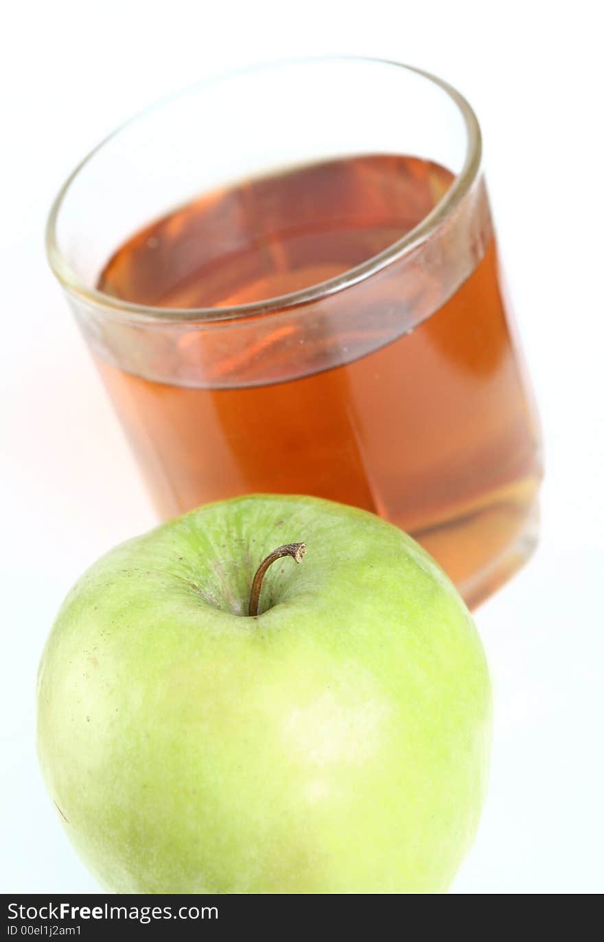 Green apple and glass of juice on a white background