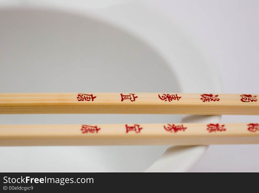 A pair of Chopsticks with red letters on a white bowl