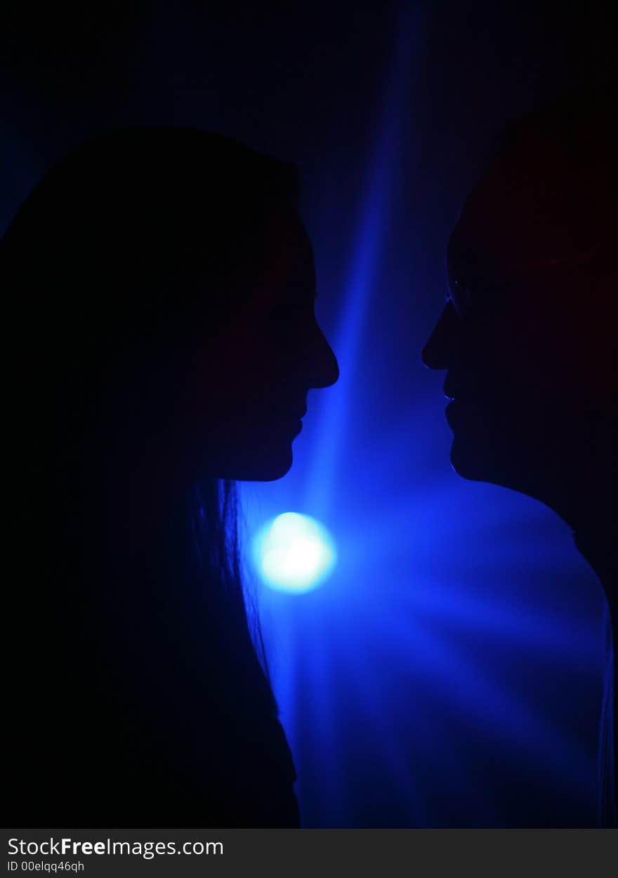 Two people in silhouete on a dark blue background. Two people in silhouete on a dark blue background