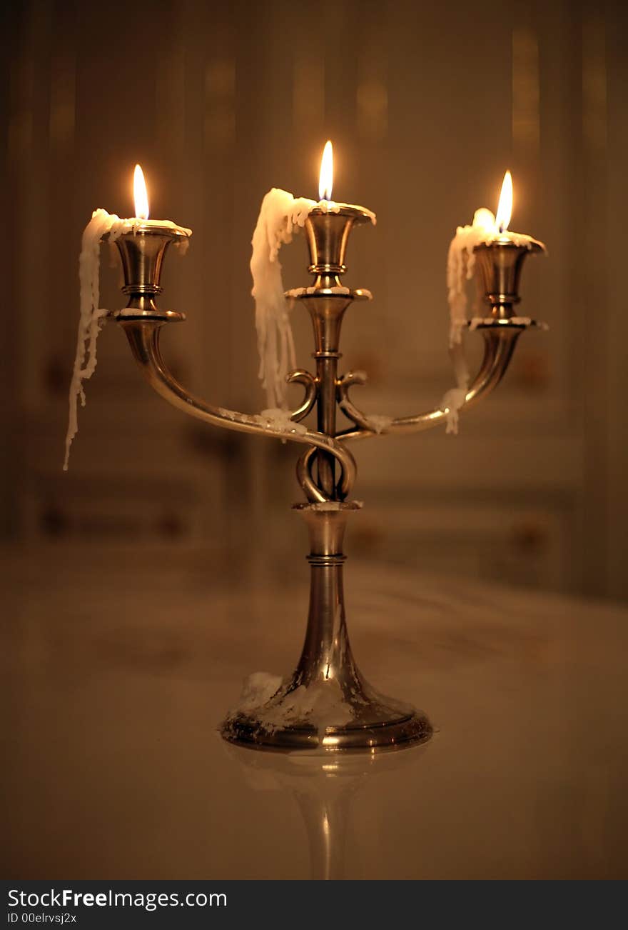 Three burning candles in an ancient gold candelabrum. Three burning candles in an ancient gold candelabrum