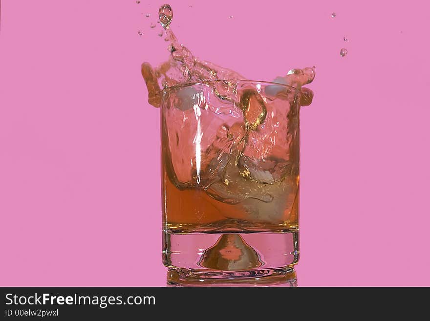Ice floe falling into scotch glass causing from the splashes. Ice floe falling into scotch glass causing from the splashes