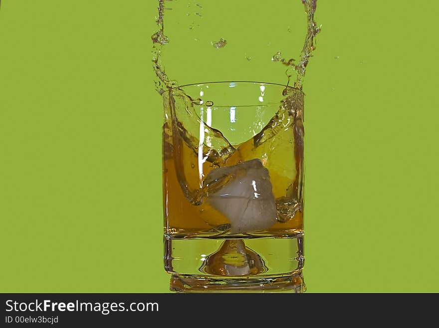 Ice floe falling into scotch glass causing from the splashes. Ice floe falling into scotch glass causing from the splashes