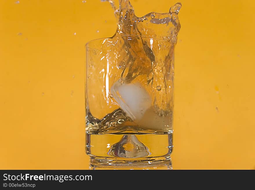 Ice floe falling into scotch glass causing from the splashes. Ice floe falling into scotch glass causing from the splashes