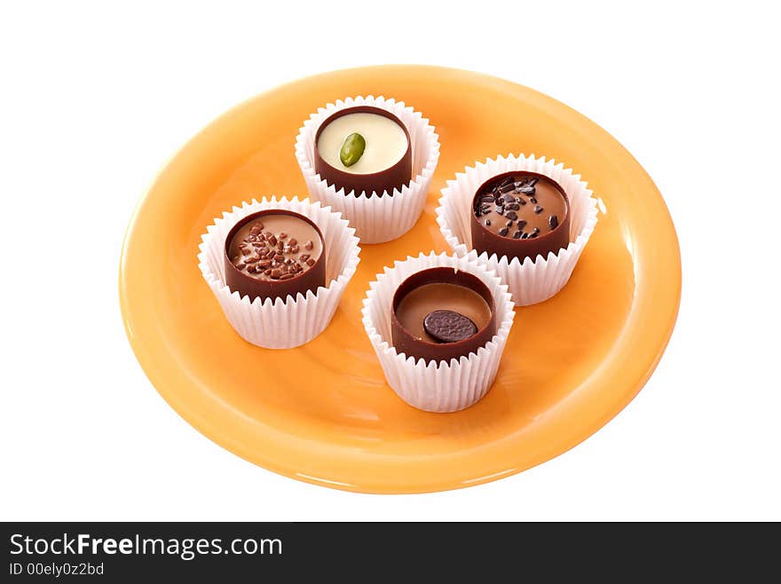 Four small candies on an orange plate. Four small candies on an orange plate