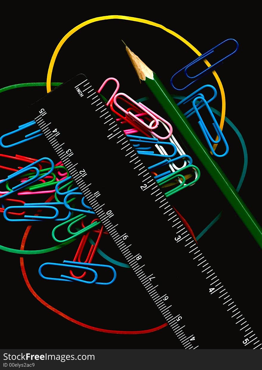 Writing subjects on a black background; a pencil; a ruler; color paper clips and a bank elastic band. Writing subjects on a black background; a pencil; a ruler; color paper clips and a bank elastic band.