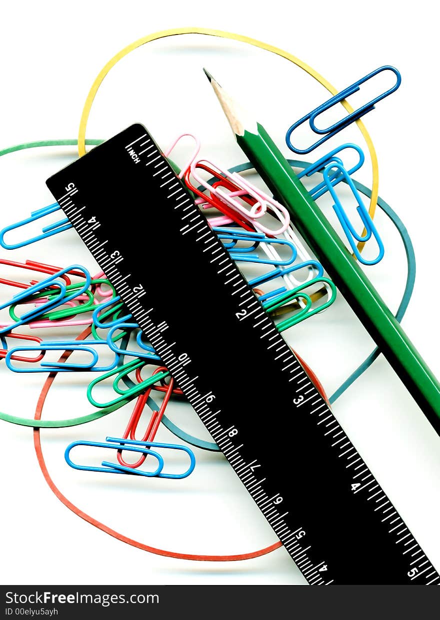 Writing subjects on a white background; a pencil; a ruler; color paper clips and a bank elastic band. Writing subjects on a white background; a pencil; a ruler; color paper clips and a bank elastic band