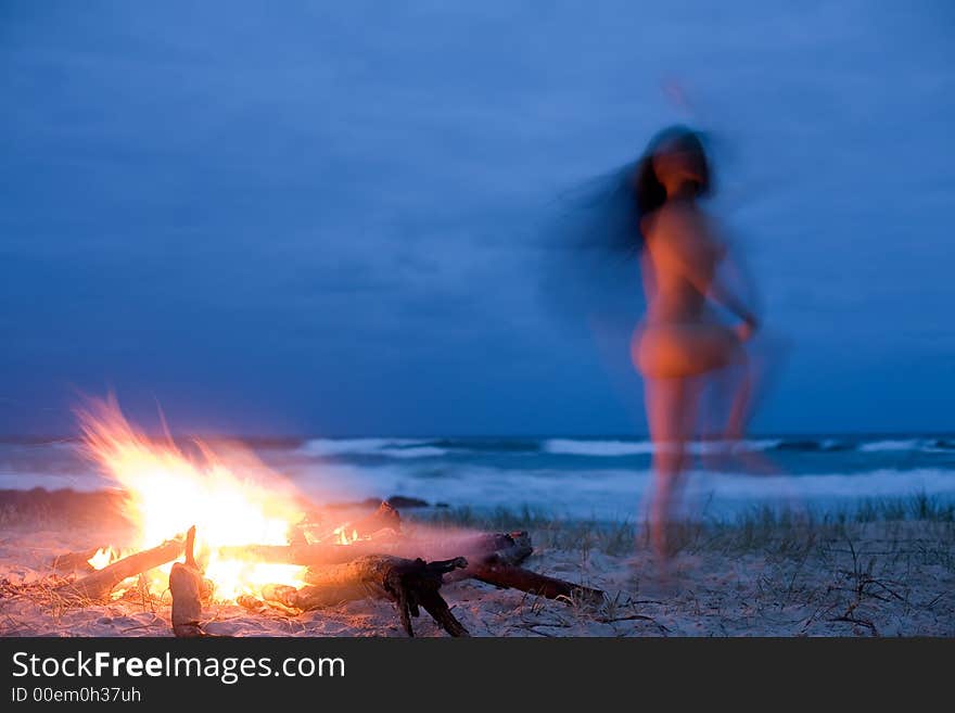 A naked woman dances around a fire. A naked woman dances around a fire