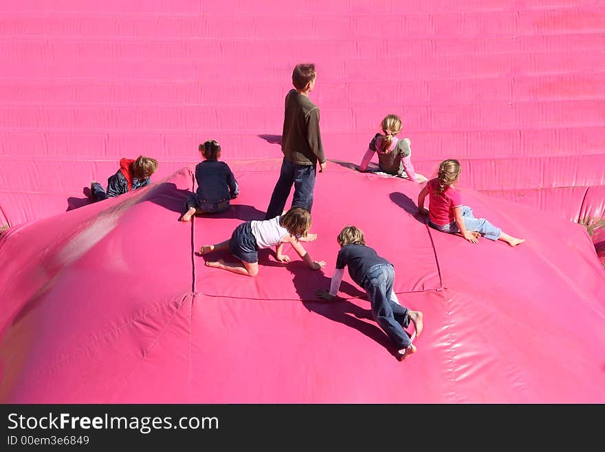 Children playing on a large air-filled cushion on the beach. Children playing on a large air-filled cushion on the beach