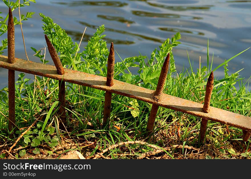 Rusty iron fence railings half buried in the ground. Rusty iron fence railings half buried in the ground.