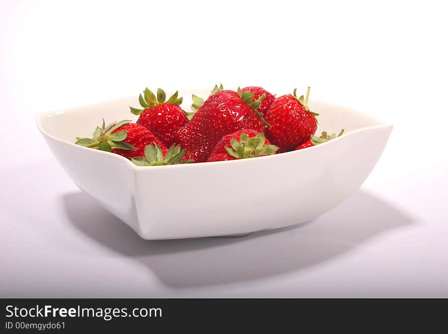 A white bowl with red strawberries on a white background. A white bowl with red strawberries on a white background