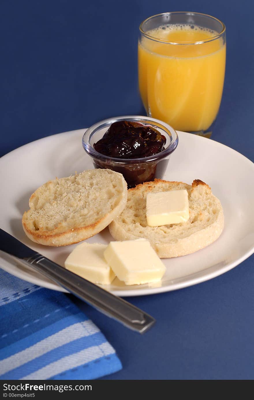 English muffin with butter, grape jam and a glass of orange juice