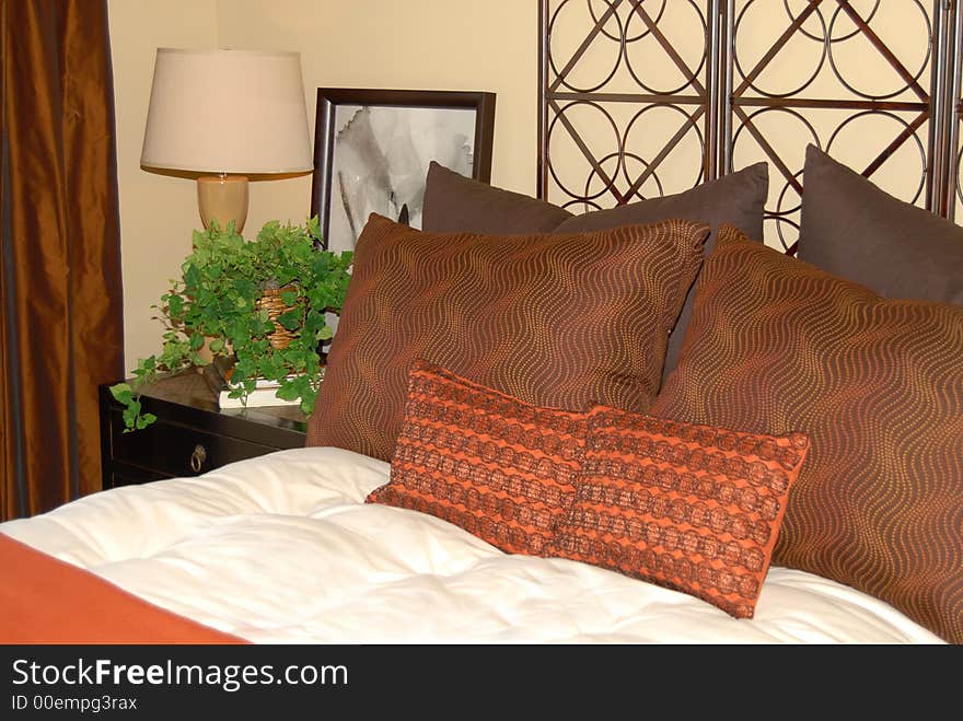 Comfortable bed with earth tone pillows and nightstand. Comfortable bed with earth tone pillows and nightstand