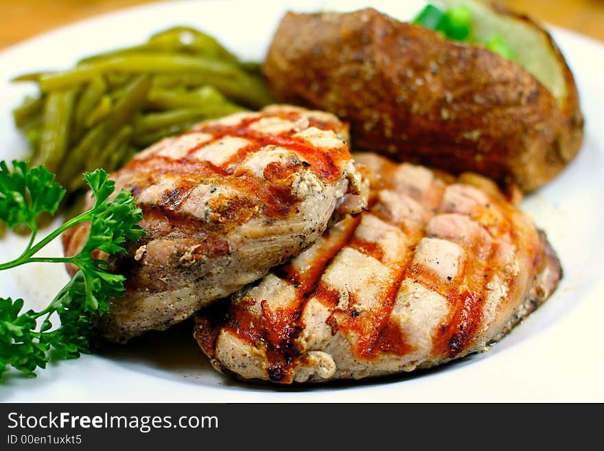 Delicious pork chop meal with a baked potato. Delicious pork chop meal with a baked potato