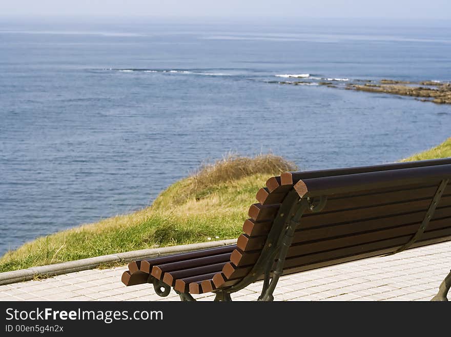 A wooden bench alone in front of the sea in a coast of Cantabria, Spain. A wooden bench alone in front of the sea in a coast of Cantabria, Spain.