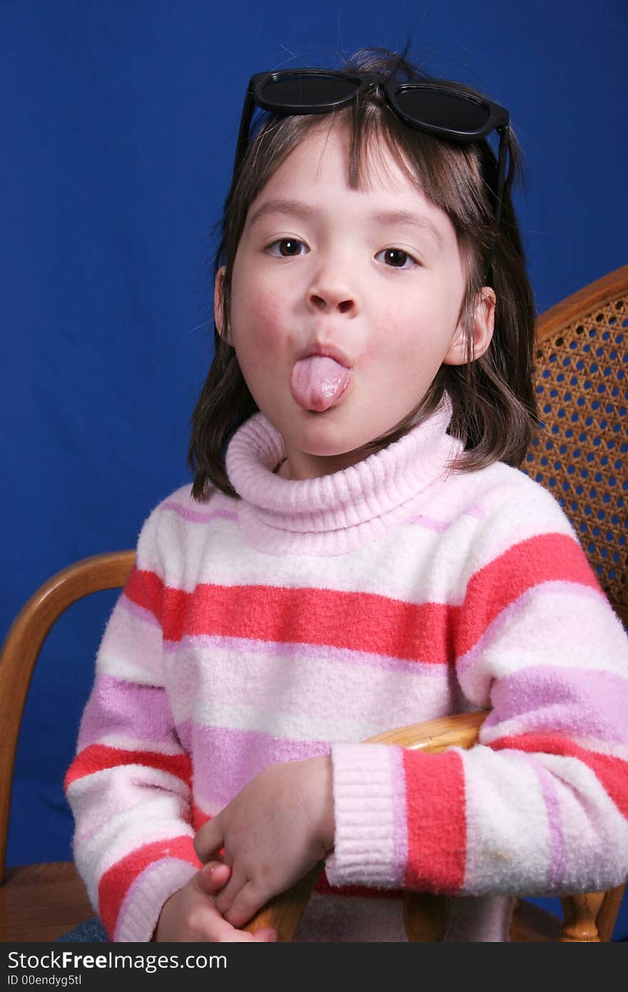 A little girl sticks out her tongue at the camera. A little girl sticks out her tongue at the camera.