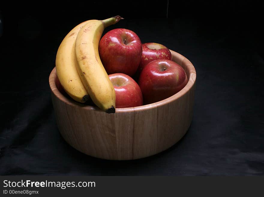 A bowl of healthy apples and bananas in low key lighting. A bowl of healthy apples and bananas in low key lighting.