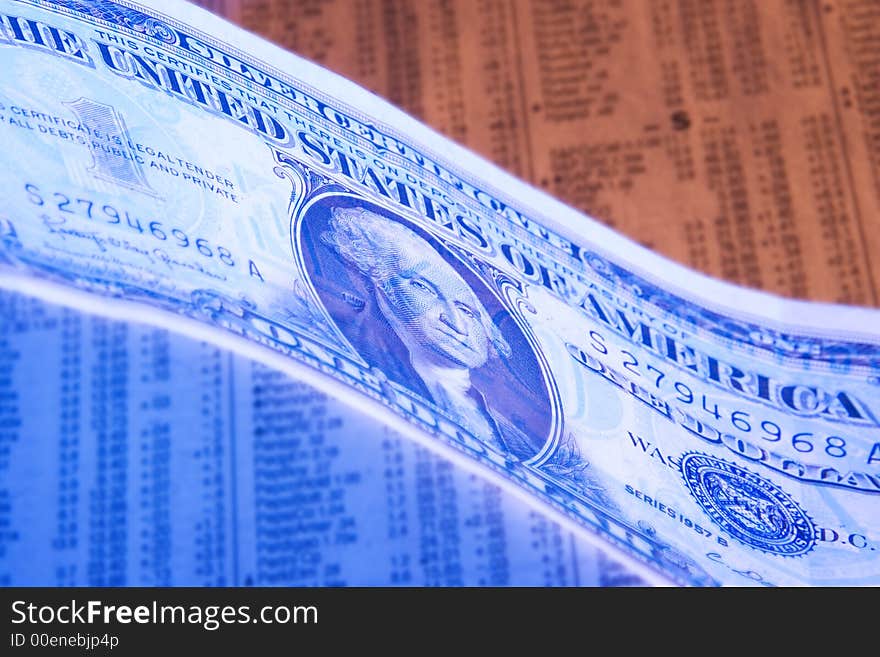 A dollar photographed with orange and blue lighting on a stock report. A dollar photographed with orange and blue lighting on a stock report.