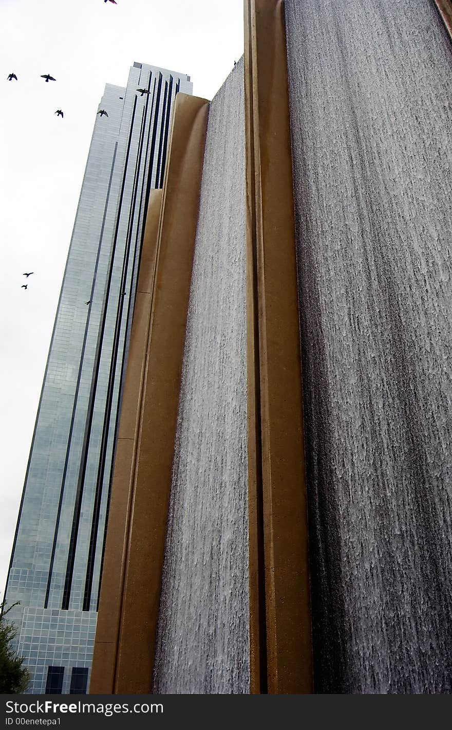 William's Tower looming in the background of a section of a man made waterfall positioned prominently in the foreground as birds circle high in the sky. William's Tower looming in the background of a section of a man made waterfall positioned prominently in the foreground as birds circle high in the sky.