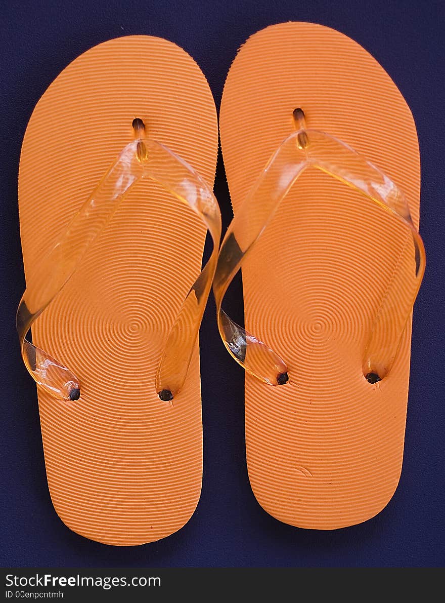 Orange Flipflops against blue background.