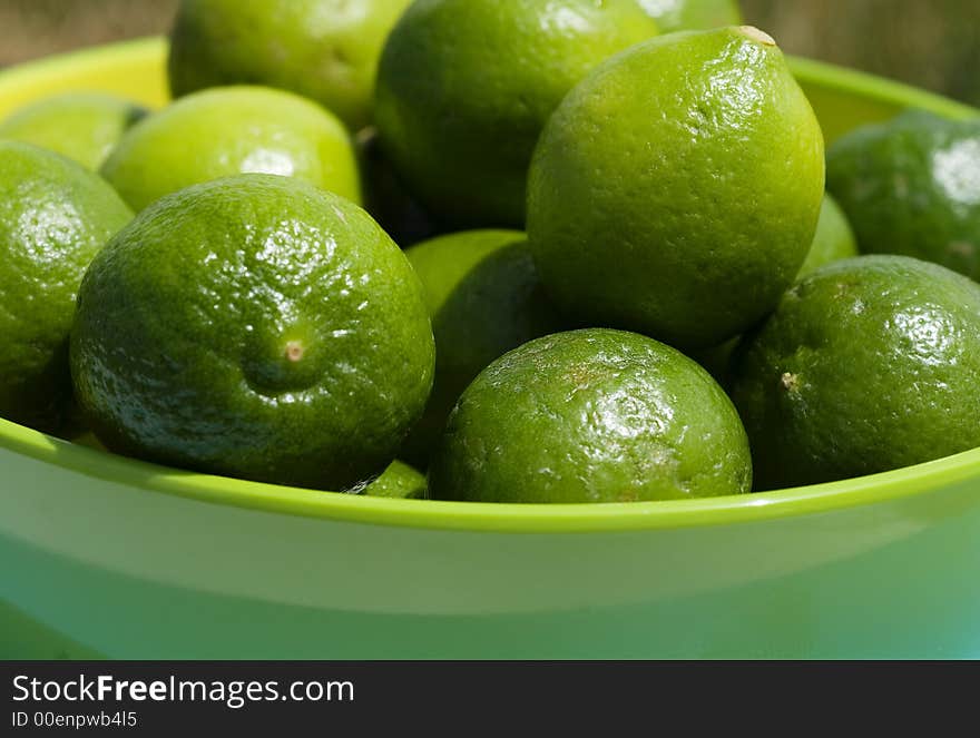 Limes up close in a green bowel in outdoor setting.