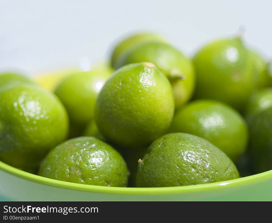 Limes up close in a green bowel in outdoor setting.