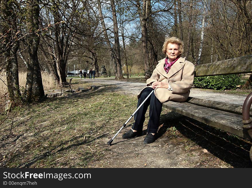 An elderly woman is enjoying the first sunrays in a park!. An elderly woman is enjoying the first sunrays in a park!