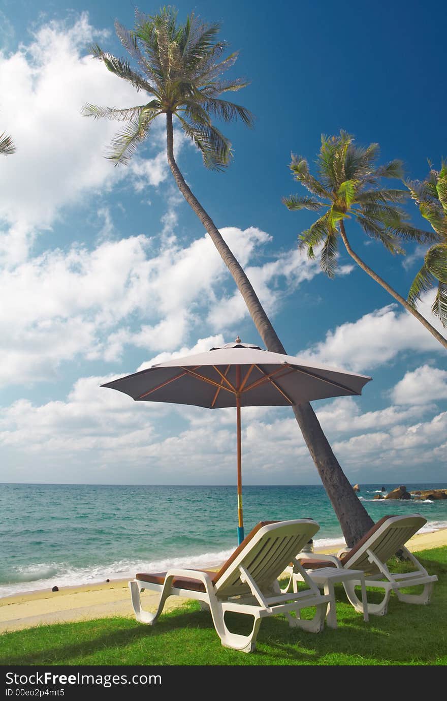 View of two chairs and  white umbrella on the beach  in the morning