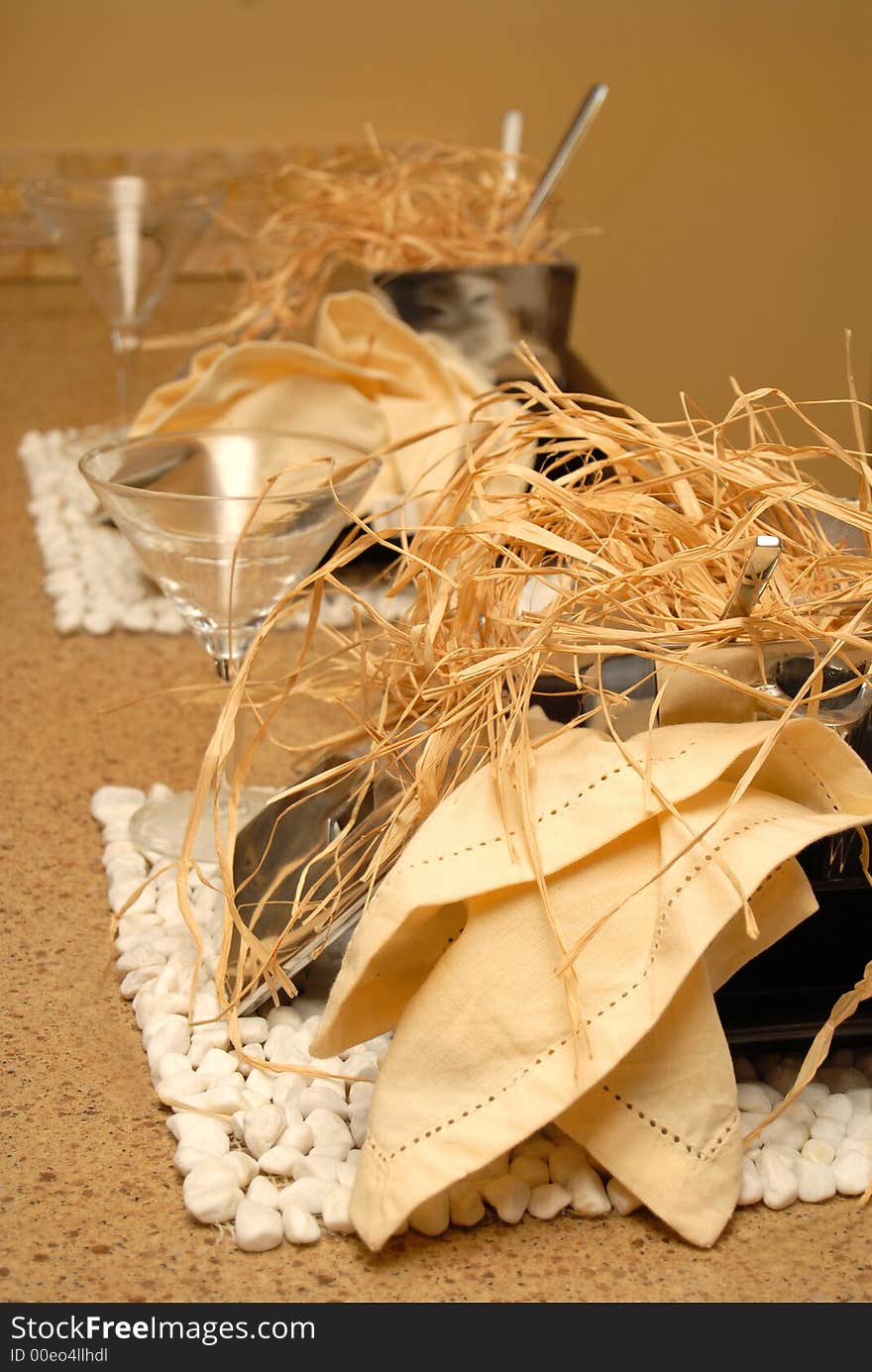 Two place settings in earth tones with wine glasses and straw. Two place settings in earth tones with wine glasses and straw