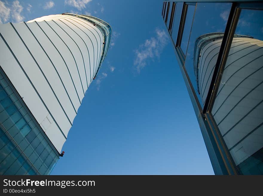 Business skyscrapers with windows fully made of glass mirroring sky and clouds, other skyscrapers and buildings. Business skyscrapers with windows fully made of glass mirroring sky and clouds, other skyscrapers and buildings.