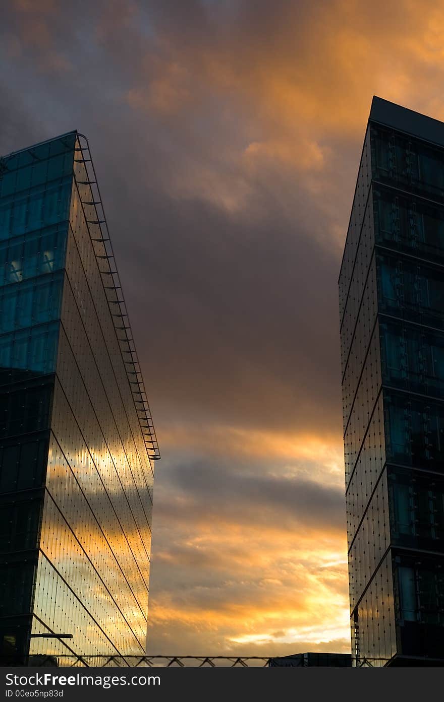 Business skyscrapers with windows fully made of glass mirroring sky and clouds, other skyscrapers and buildings.