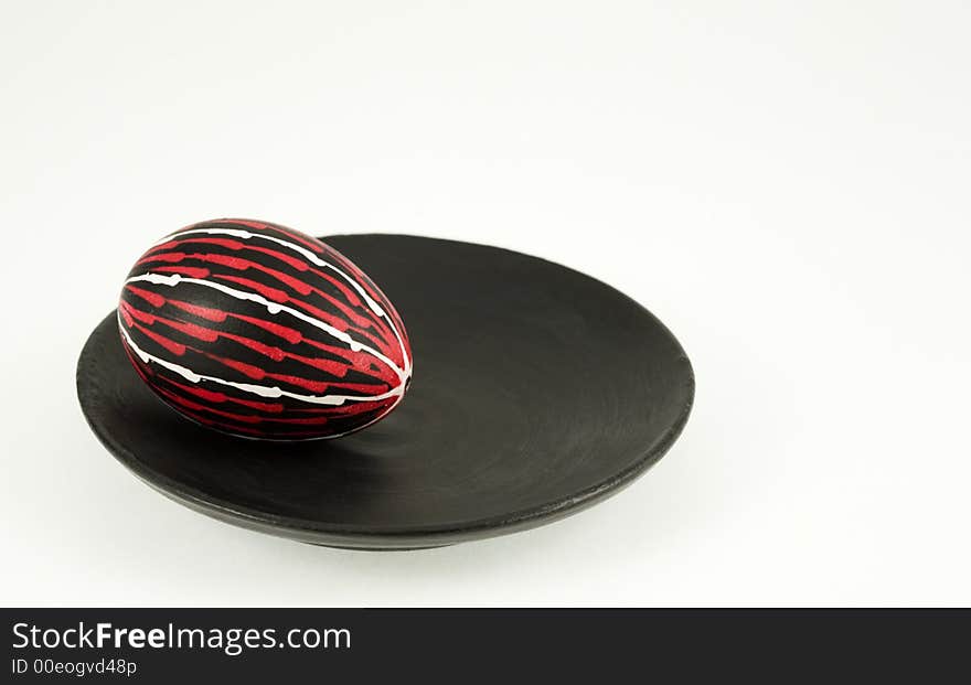 Hand colored egg on a black plate over the white background. Hand colored egg on a black plate over the white background