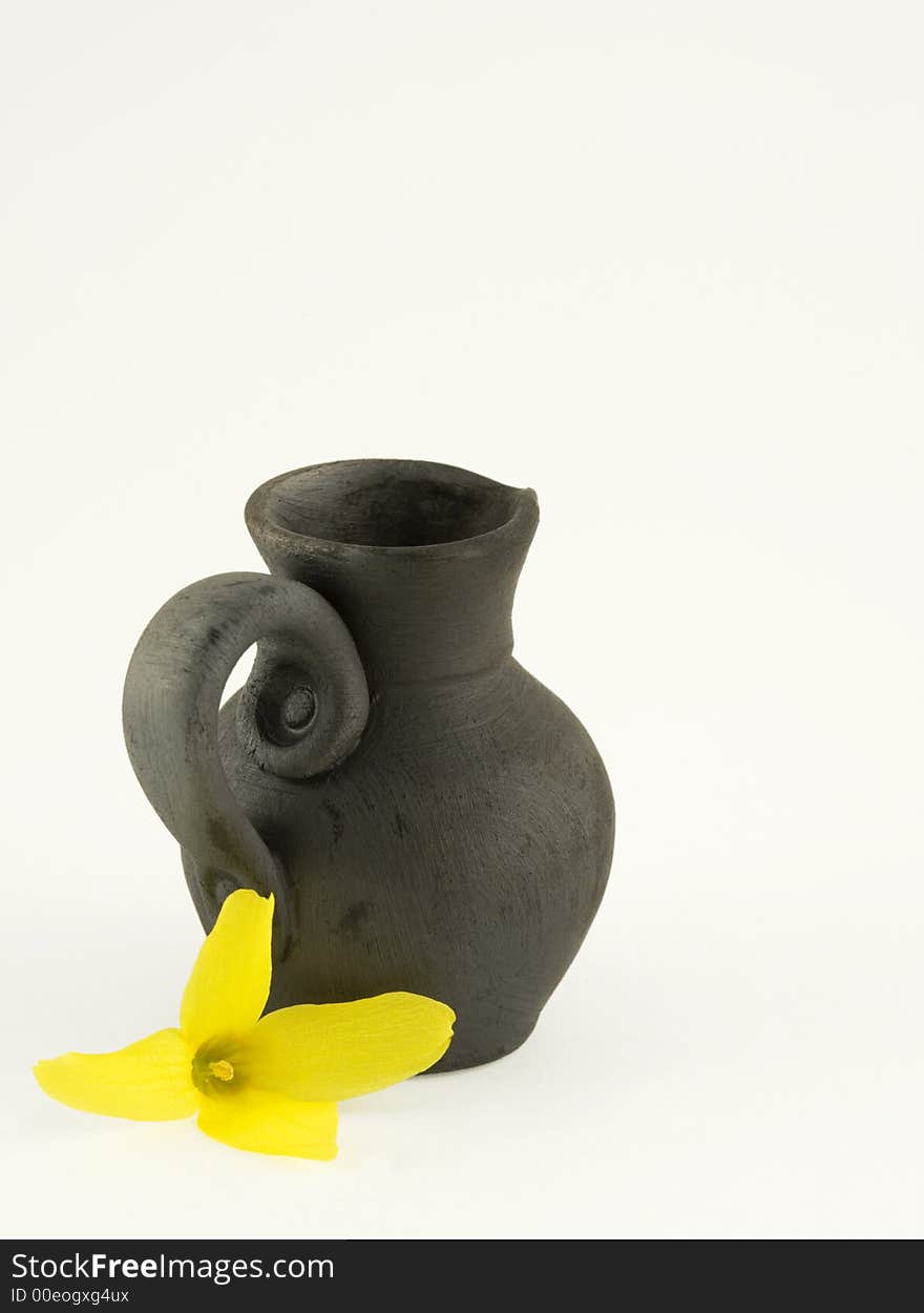 Black ceramic hand-made jar with a yellow flower - forsythia. Black ceramic hand-made jar with a yellow flower - forsythia