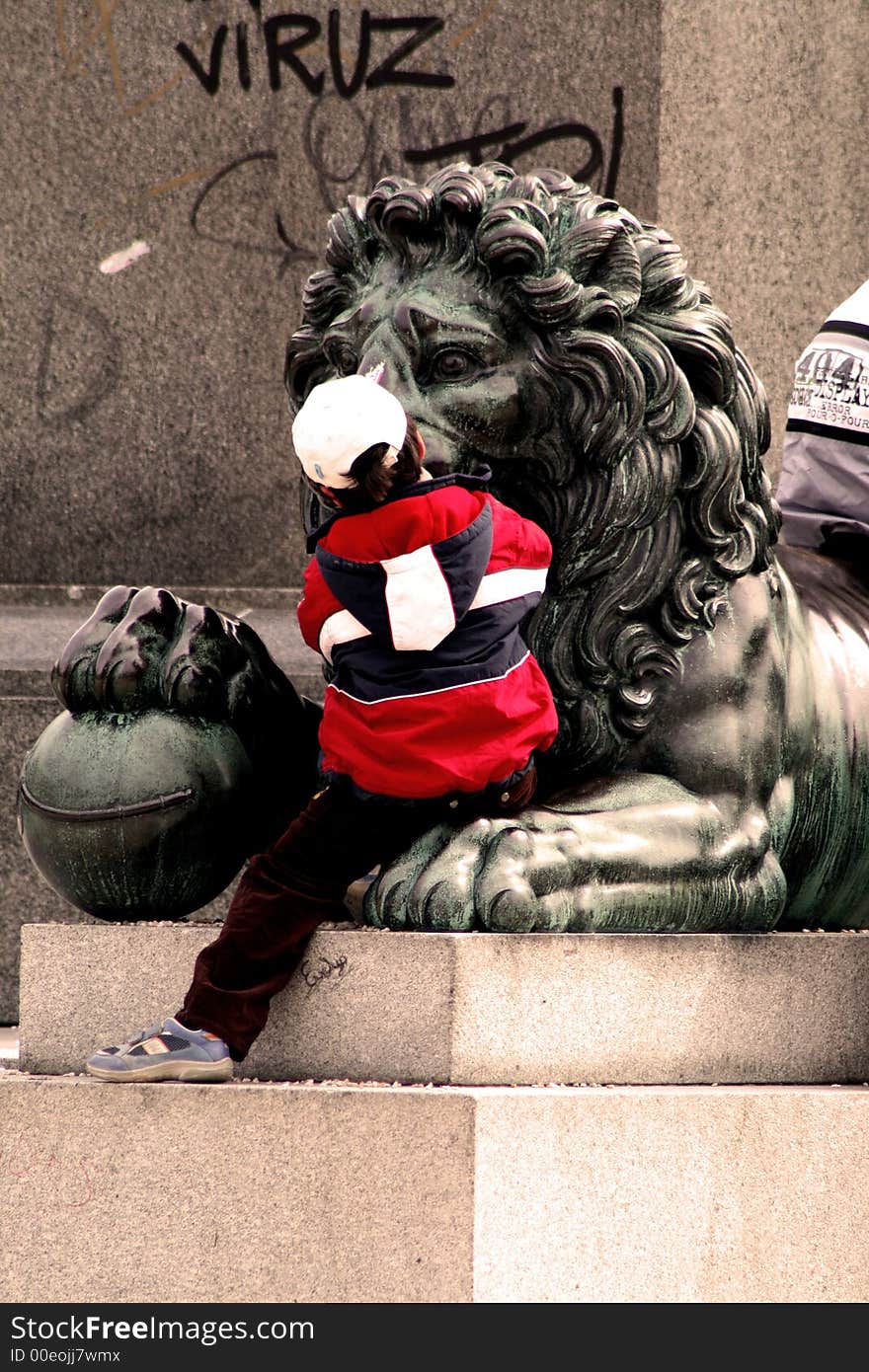 Little boy sitting on the paw of bronze lion. Little boy sitting on the paw of bronze lion