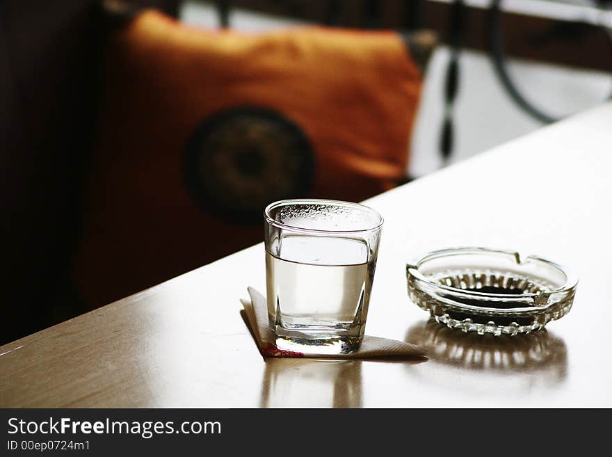 Glass and ashtray on table