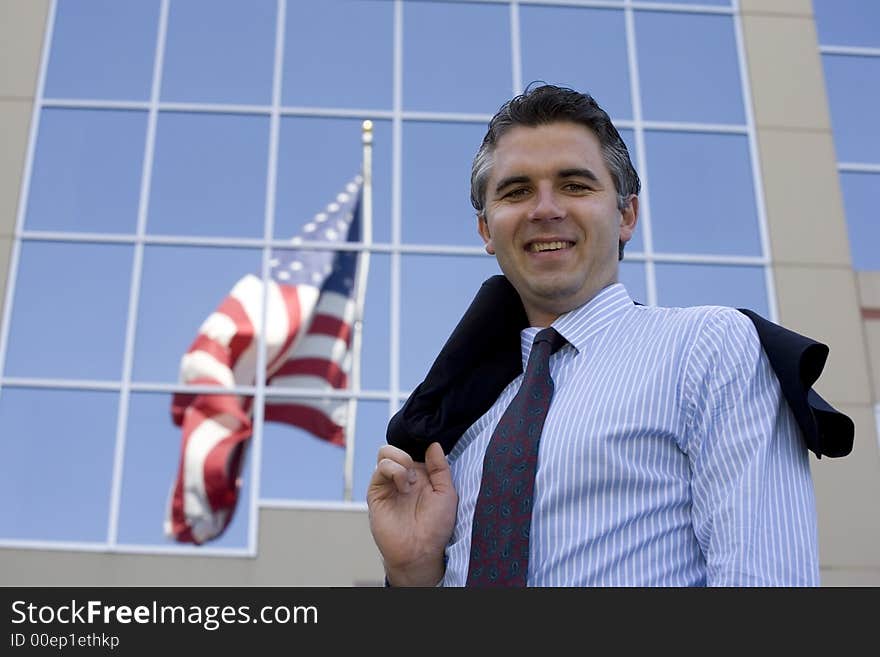 Businessman standing outside the office building with the American flag reflection in the windows. Businessman standing outside the office building with the American flag reflection in the windows