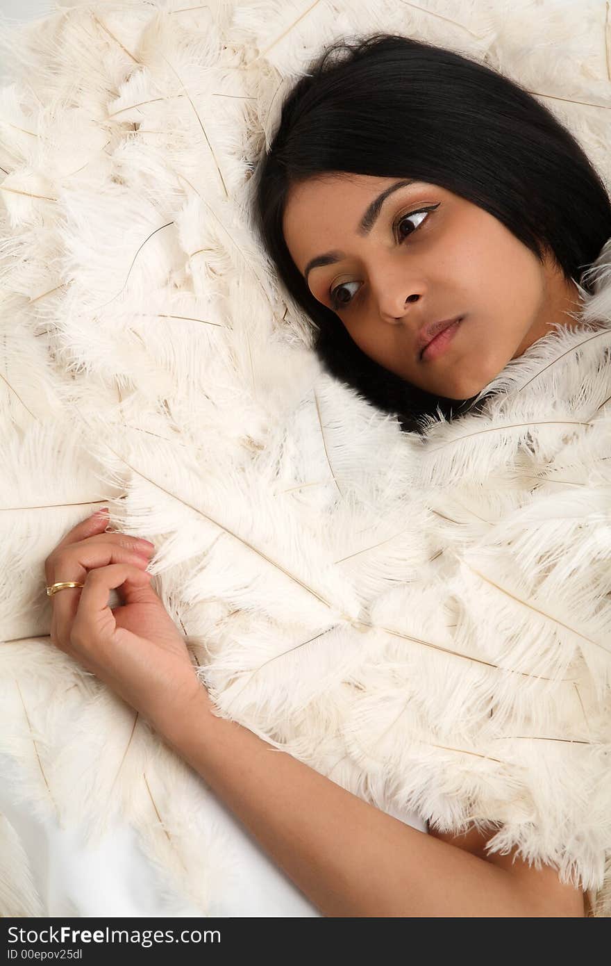 Young asian woman lying on hundreds of ostrich feathers. Young asian woman lying on hundreds of ostrich feathers