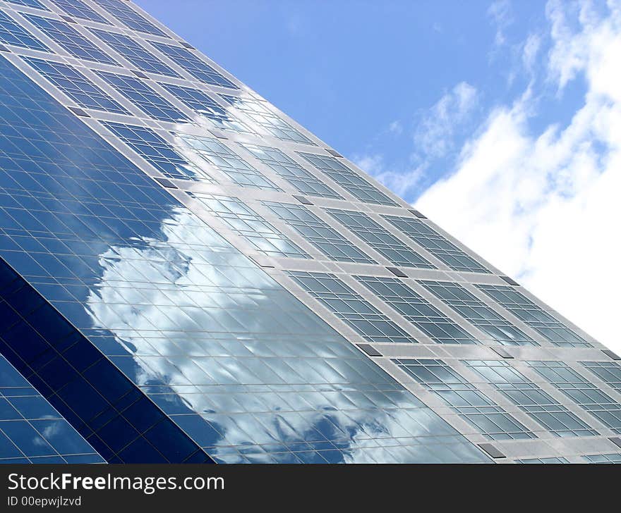 High quality abstract image of blue office building with clouds reflecting in the glass