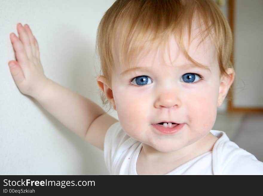 A baby girl leaning against a wall. A baby girl leaning against a wall.