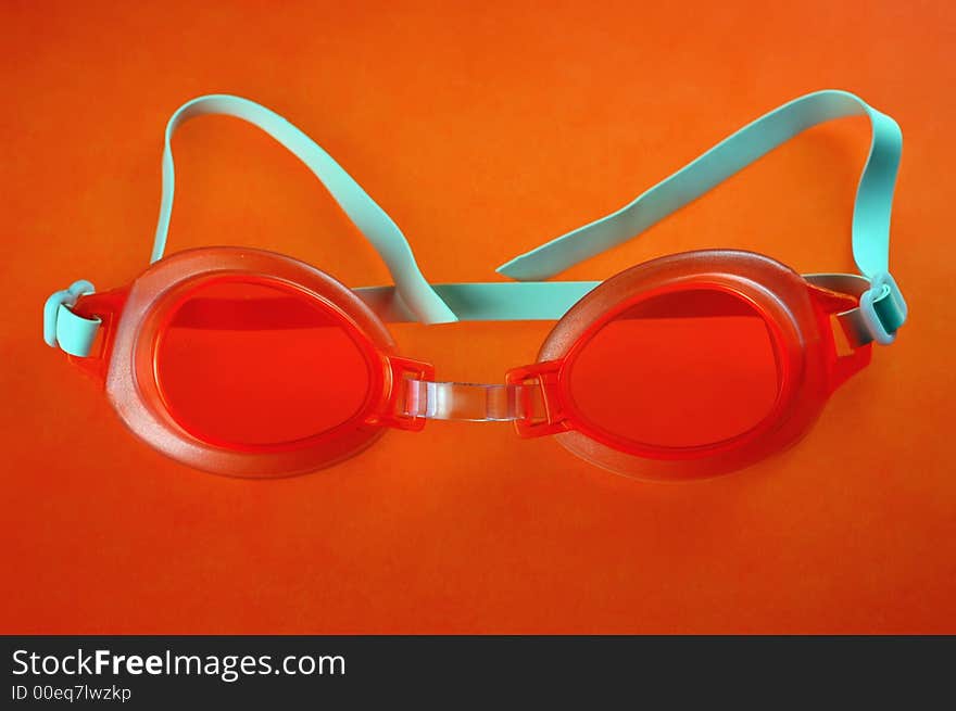 Pair of orange swimming goggles on an orange background