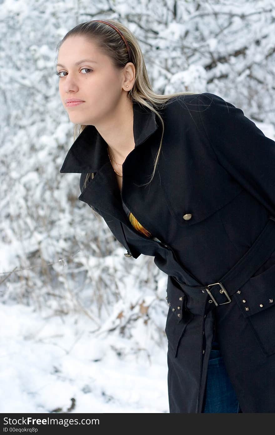 Young girl in winter park in black raincoat. Young girl in winter park in black raincoat