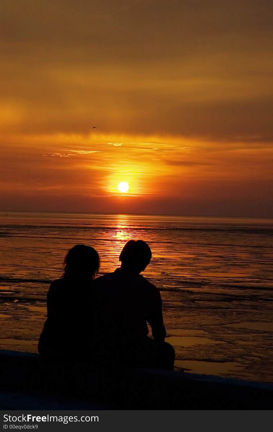 Couple sitting at sea side watching sun set . Couple sitting at sea side watching sun set .