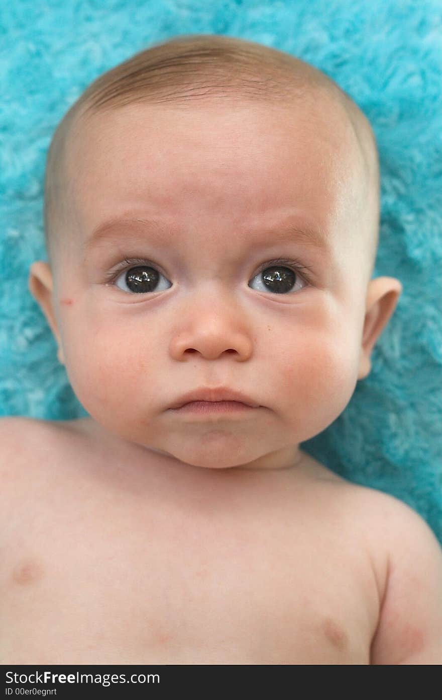 Image of beautiful 6 month old baby boy lying on a fuzzy turquoise blanket. Image of beautiful 6 month old baby boy lying on a fuzzy turquoise blanket