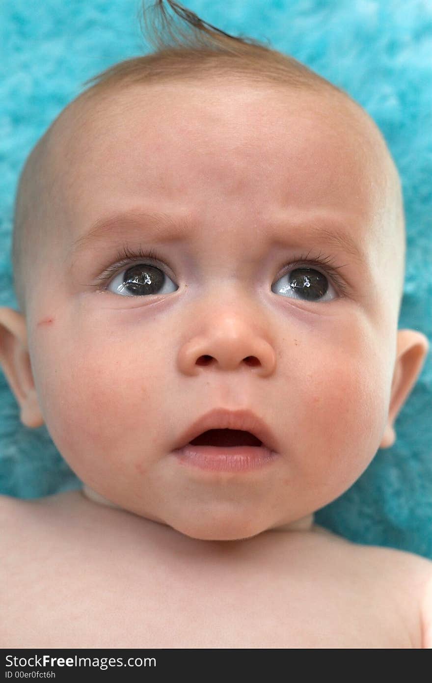 Image of beautiful 6 month old baby boy lying on a fuzzy turquoise blanket. Image of beautiful 6 month old baby boy lying on a fuzzy turquoise blanket