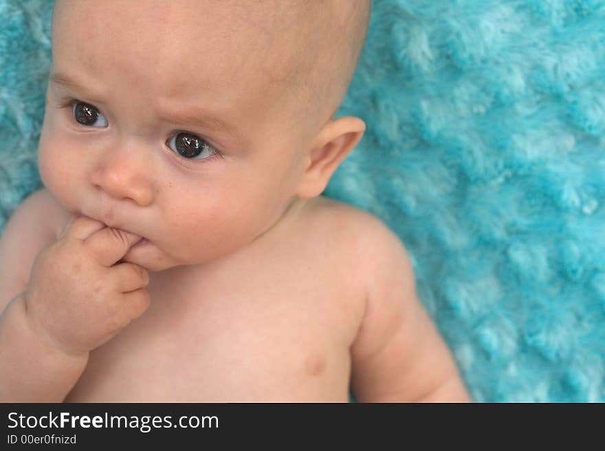 Image of beautiful 6 month old baby boy lying on a fuzzy turquoise blanket. Image of beautiful 6 month old baby boy lying on a fuzzy turquoise blanket