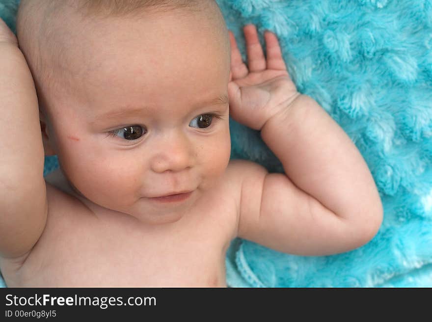 Image of beautiful 6 month old baby boy lying on a fuzzy turquoise blanket. Image of beautiful 6 month old baby boy lying on a fuzzy turquoise blanket