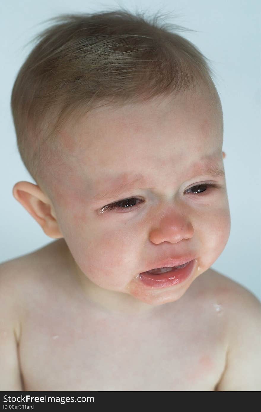 Image of crying baby sitting in front of a white background