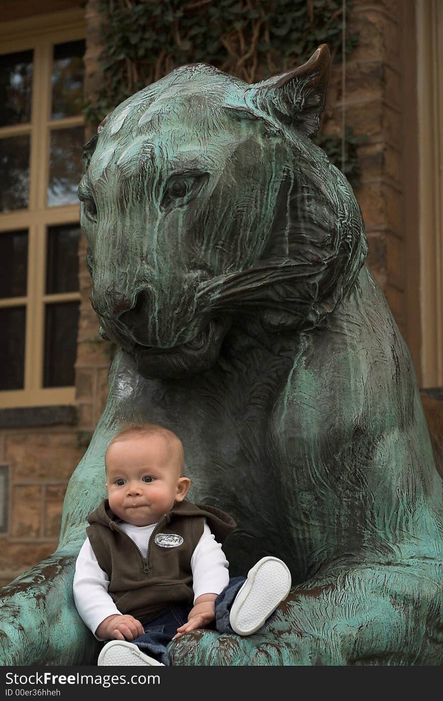 Image of cute baby sitting in front of a lion sculpture. Image of cute baby sitting in front of a lion sculpture