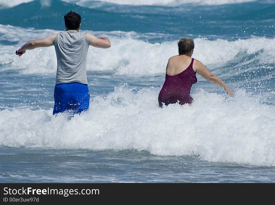 Two people walking into the surf and waves on a Florida beach. Two people walking into the surf and waves on a Florida beach